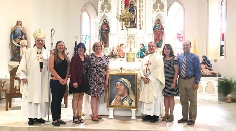 Archbishop Michael Jackels (far left) poses with a group of school administrators and supporters on the altar of St. Wenceslaus Church in Spillville. The portrait of the saint in the center of the photo was painted by artist Chris Graziano.