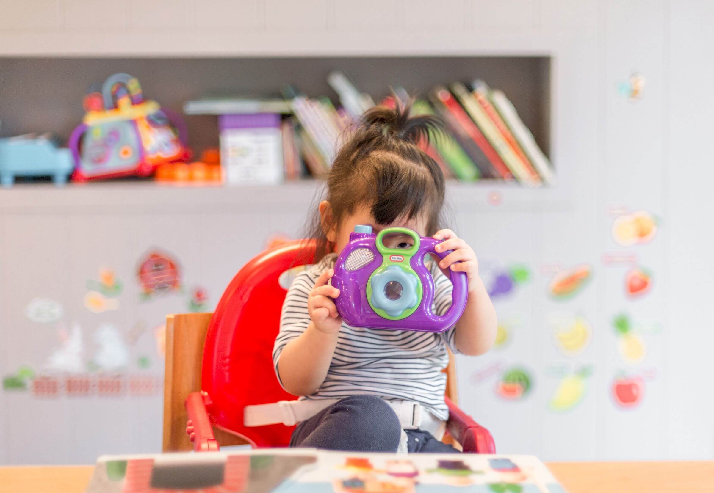 Little girl holding a purple camera 